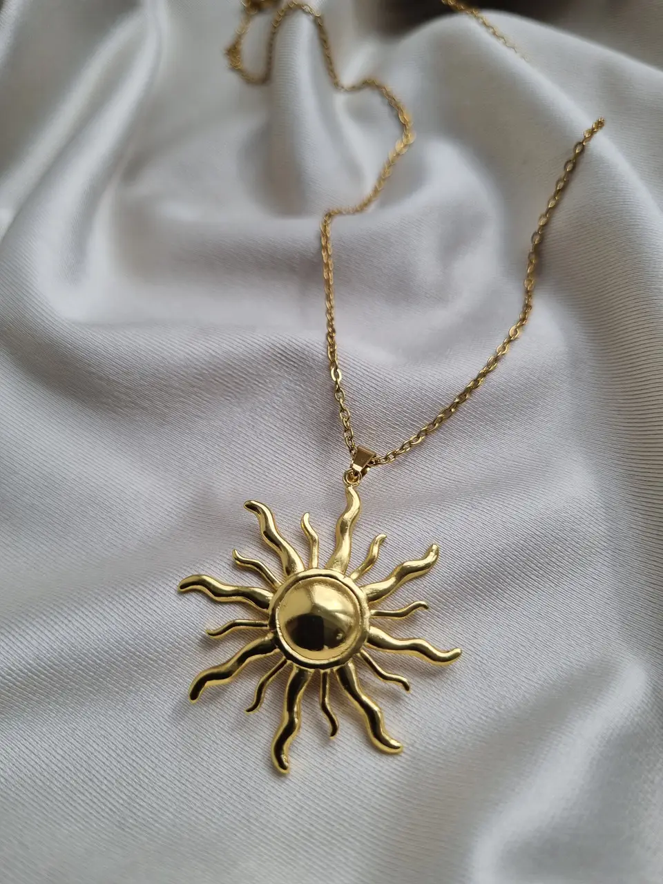 Large gold sun pendant with wavy rays on a fine chain