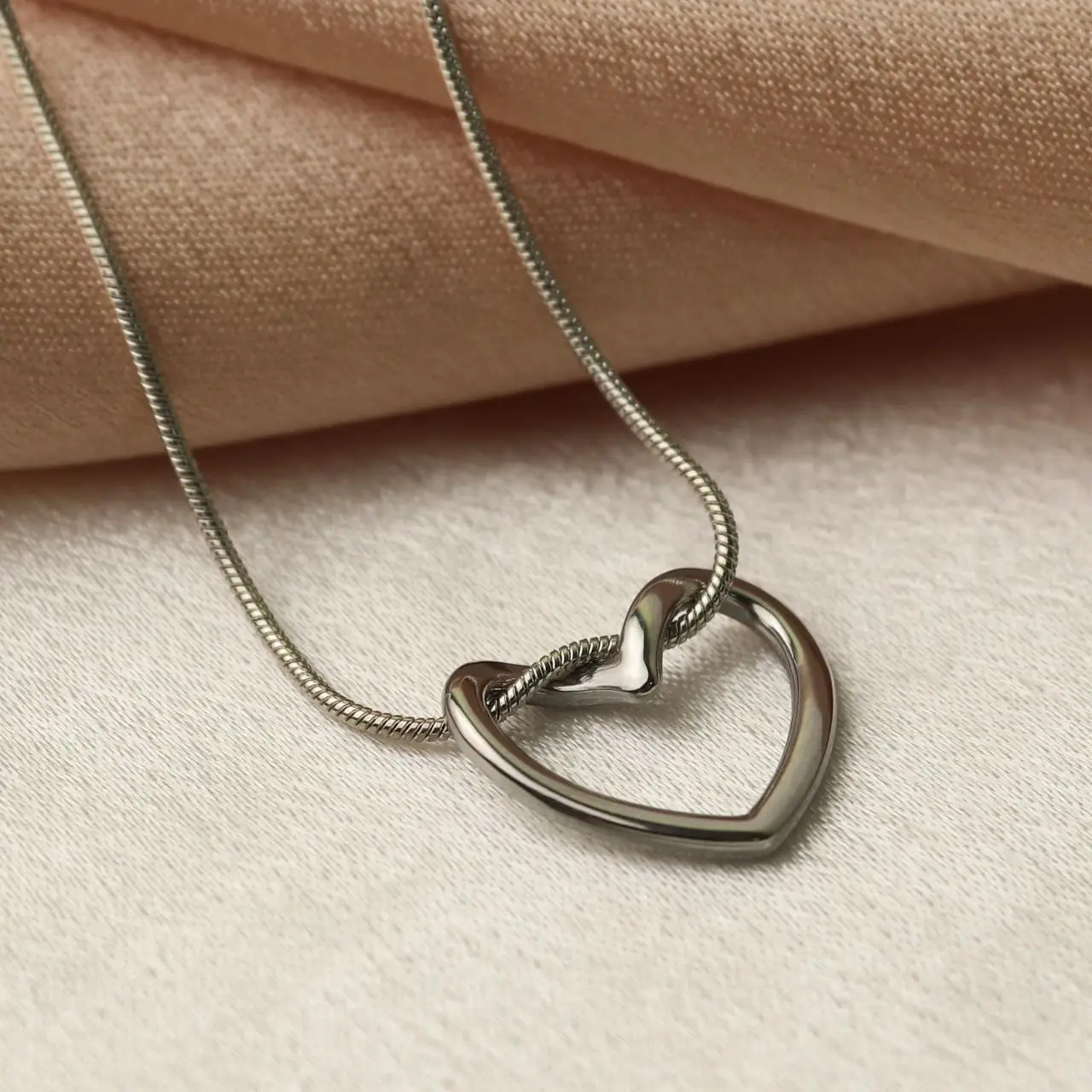 Silver open heart threaded onto a thin snake chain